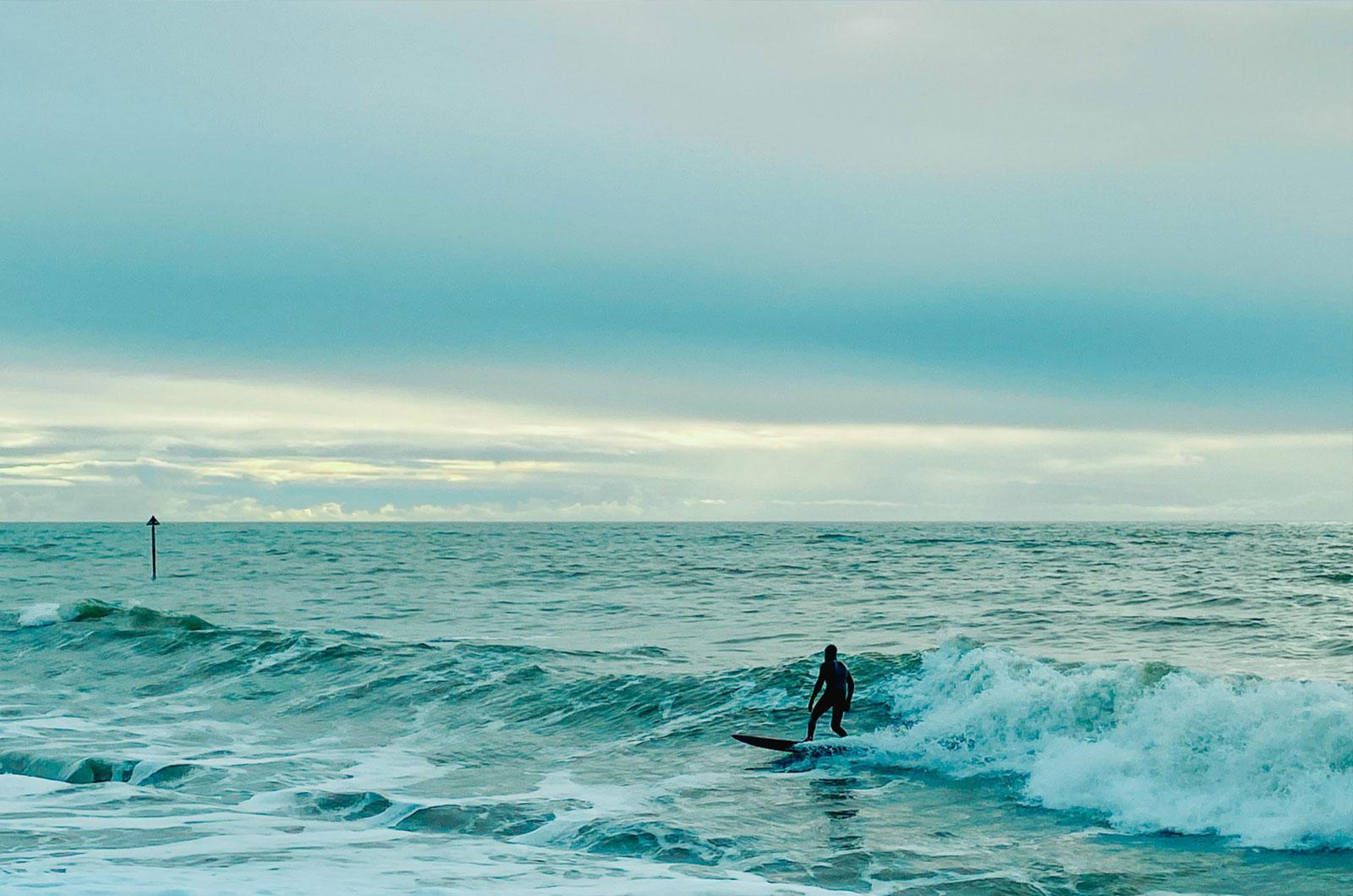 Image of a person surfing on the ocean with a sign in the background