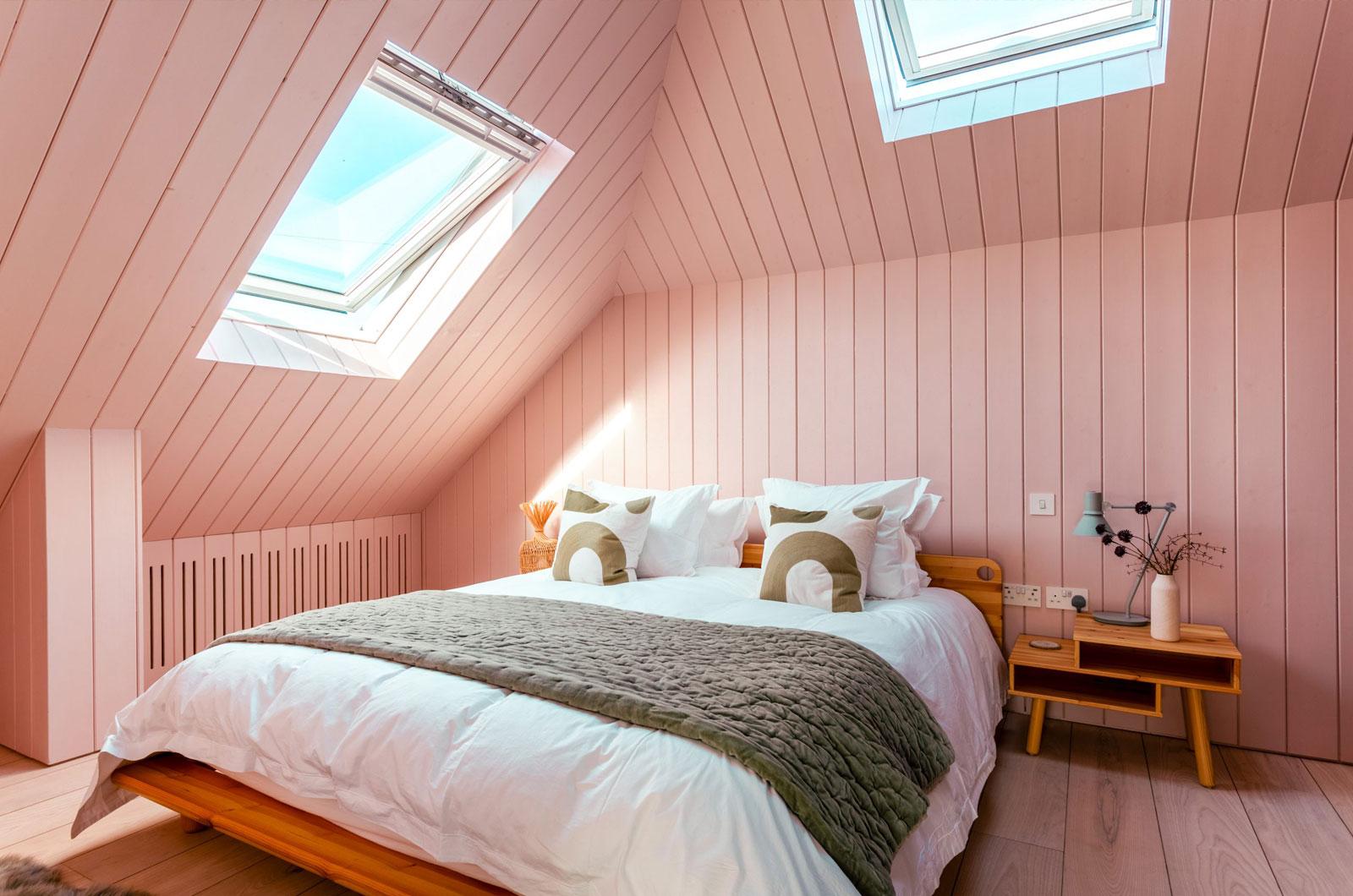 Image of a cosy bed in a pink room with a skylight