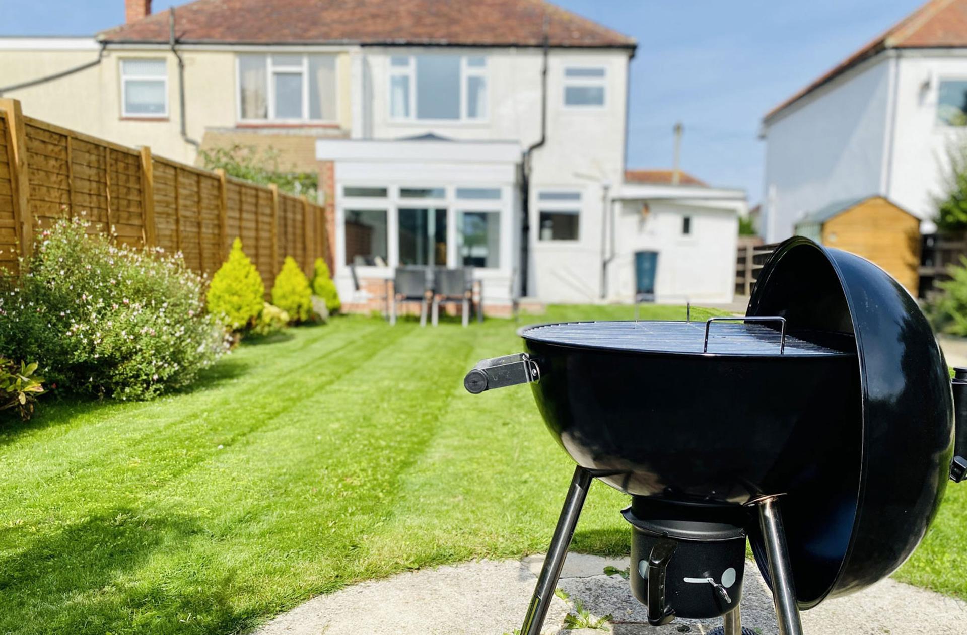 Ocean Grove Image A close up of the barbeque in the spacious garden. The house can be seen in the background with a set of chairs and a table just in front.