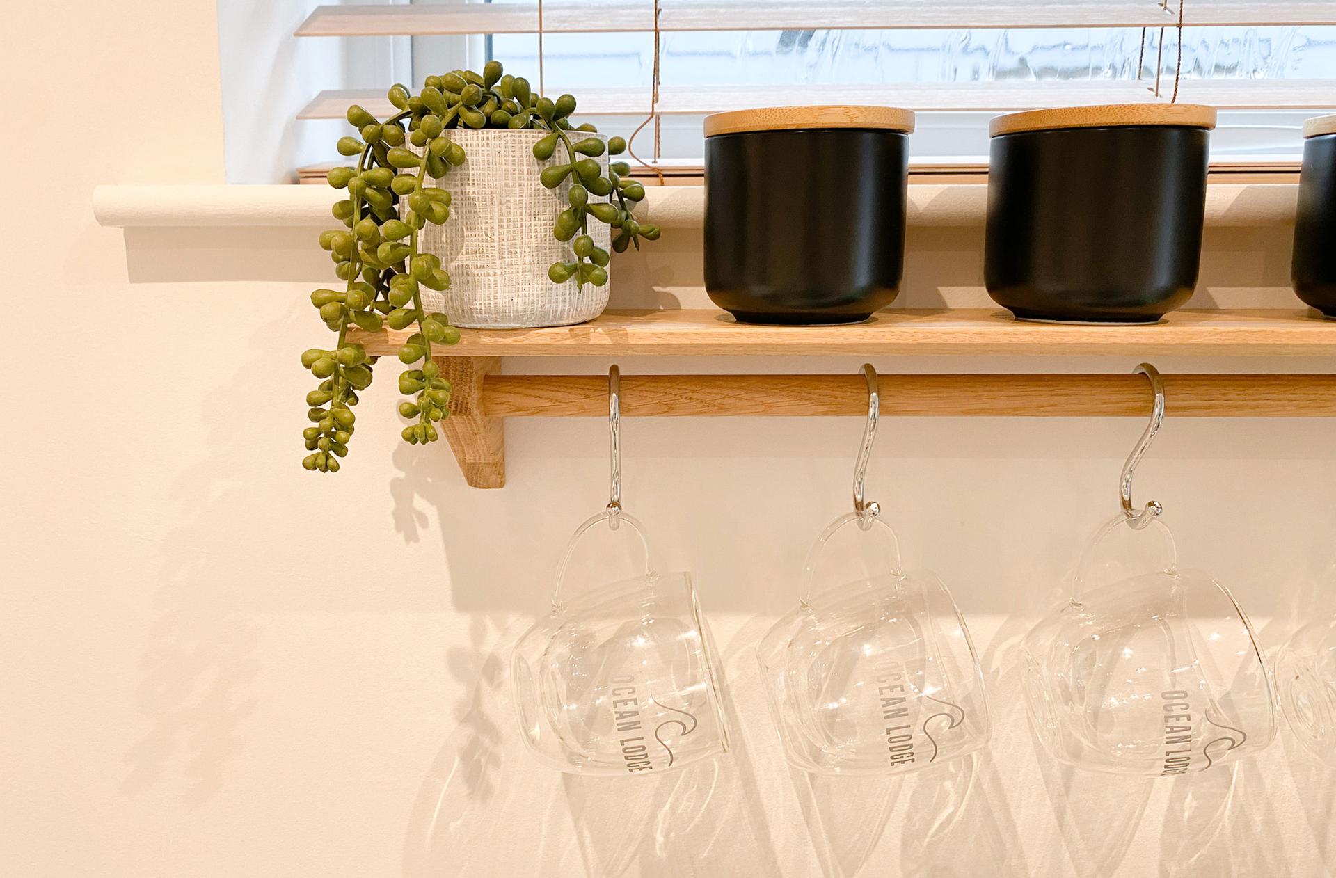 Ocean Lodge Image A shelf featuring a set of candles and a small hanging succulent plant