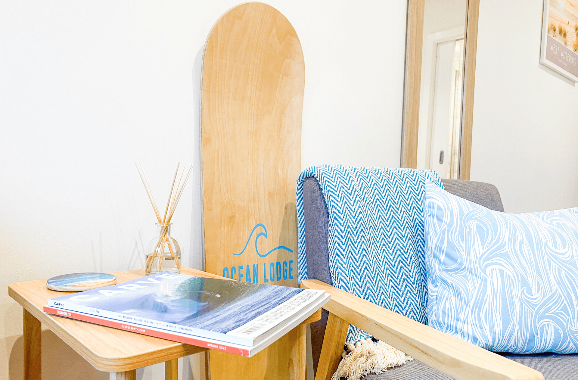 Ocean Lodge Image A close up of a set of chairs with the words Ocean Lodge written on a surfboard styled sign sits just behind the chairs.