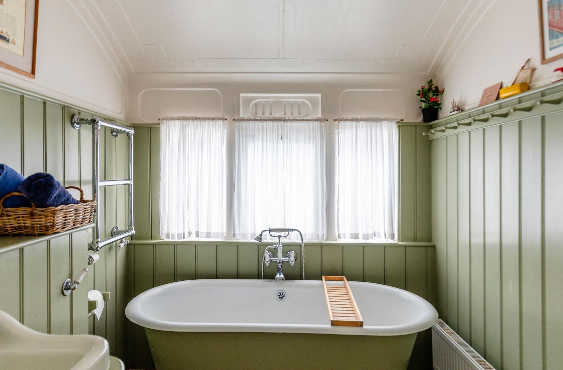 The Dodo Image A muted green bathroom featuring a freestanding bath. The room is styled in muted colours.