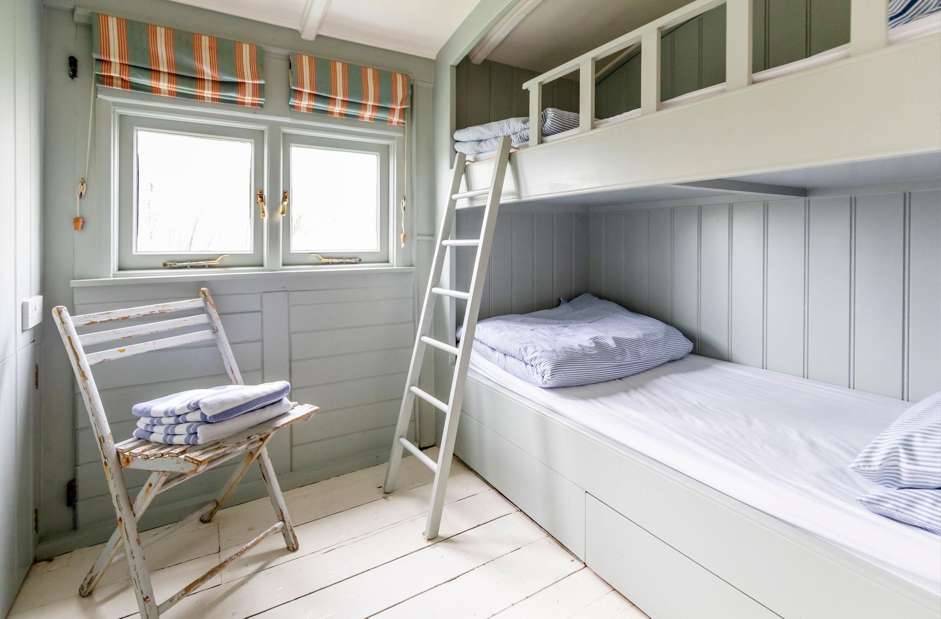 The Dodo Image A section of the bedroom with a bunk bed featuring two beds. Light pours into the room styled in blue.