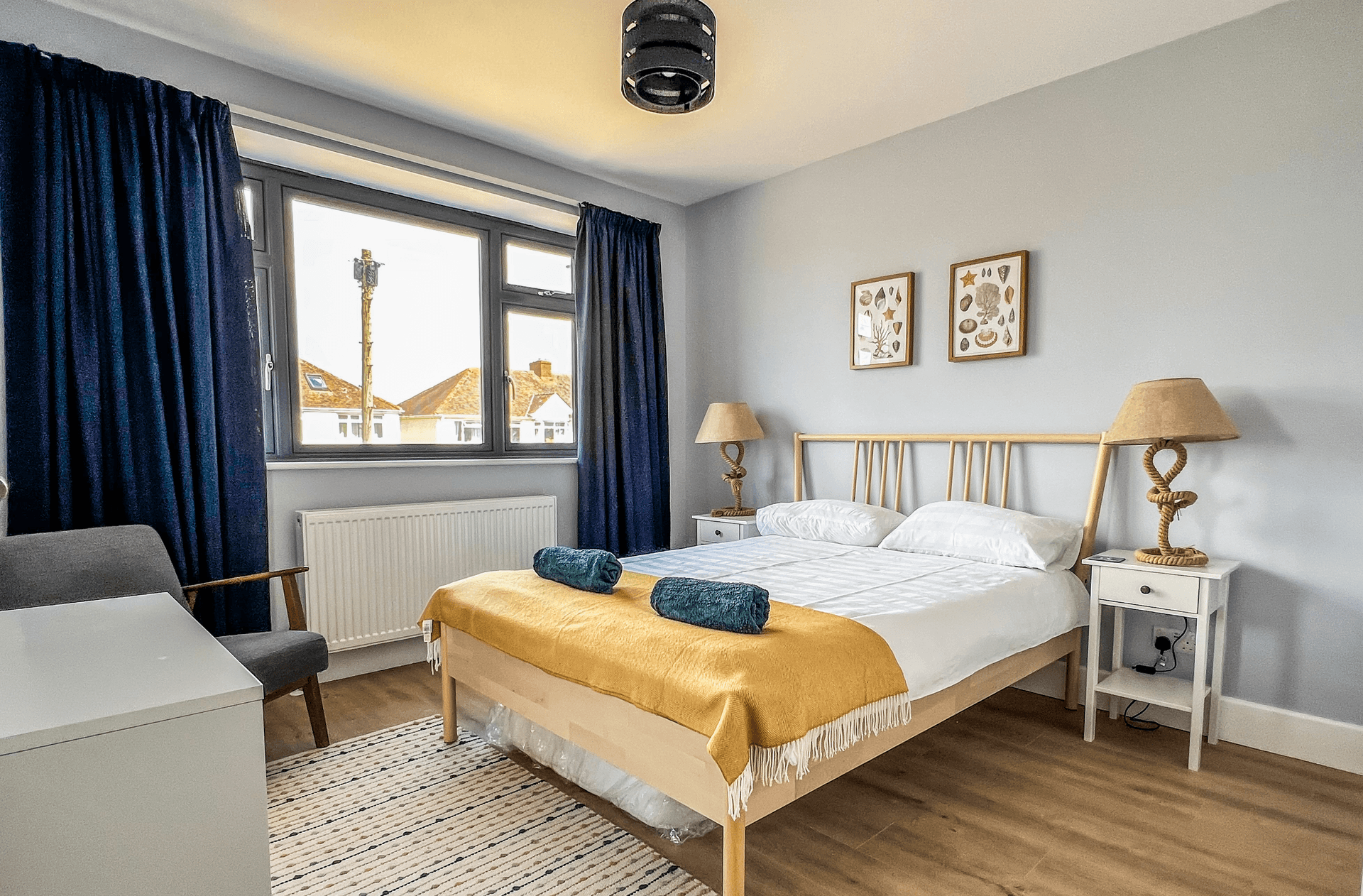Ocean Grove Image A large double bed sits at the centre of a bedroom. A set of towels are rolled up on the centre of the bed.